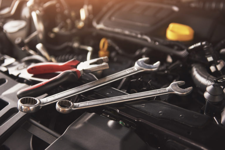 Mechanic hand checking and fixing a broken car in car service garage